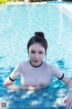 A woman in a white bodysuit is sitting in a pool.