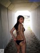 A woman in a black bikini standing in a tunnel.