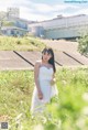 A woman in a white dress standing in a field.