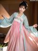 A woman in a pink and blue hanbok is posing for a picture.