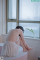 A woman sitting on a window sill with her back to the camera.