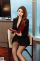 A woman sitting on a chair holding a red folder.