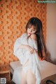 A woman in a white shirt is posing on a bed.