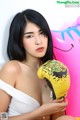 A woman in a white top holding a yellow boxing glove.