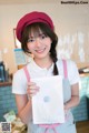 A woman in a pink hat and apron holding a white bag.