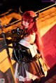 A woman dressed as a demon holding a sword.