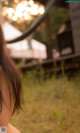 A woman with long brown hair sitting in the grass.