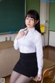 A woman in a white shirt and black skirt posing for a picture.
