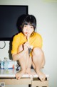 A woman sitting on top of a desk holding a toothbrush.