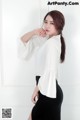 A woman in a white blouse and black skirt posing for a picture.