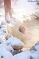 A woman in a hot tub in the snow.