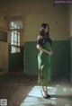 A woman in a green dress standing in an abandoned building.