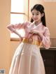 A woman in a pink and white hanbok is posing for a picture.